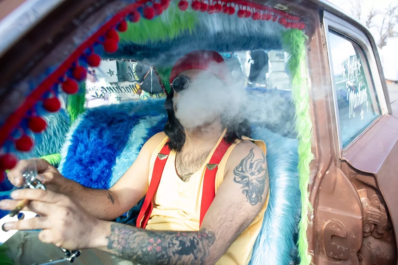 A man dressed as Cheech Marin smokes a joint in his Cadillac at the Denver 420 Fest