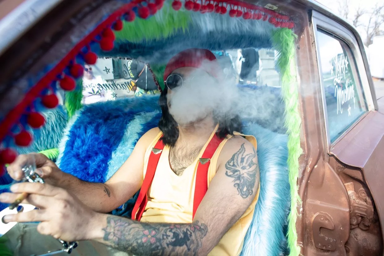 A man dressed as Cheech Marin smokes a joint in his Cadillac at the Denver 420 Fest
