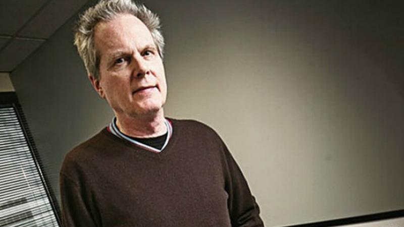 A portrait of a man in a brown sweater