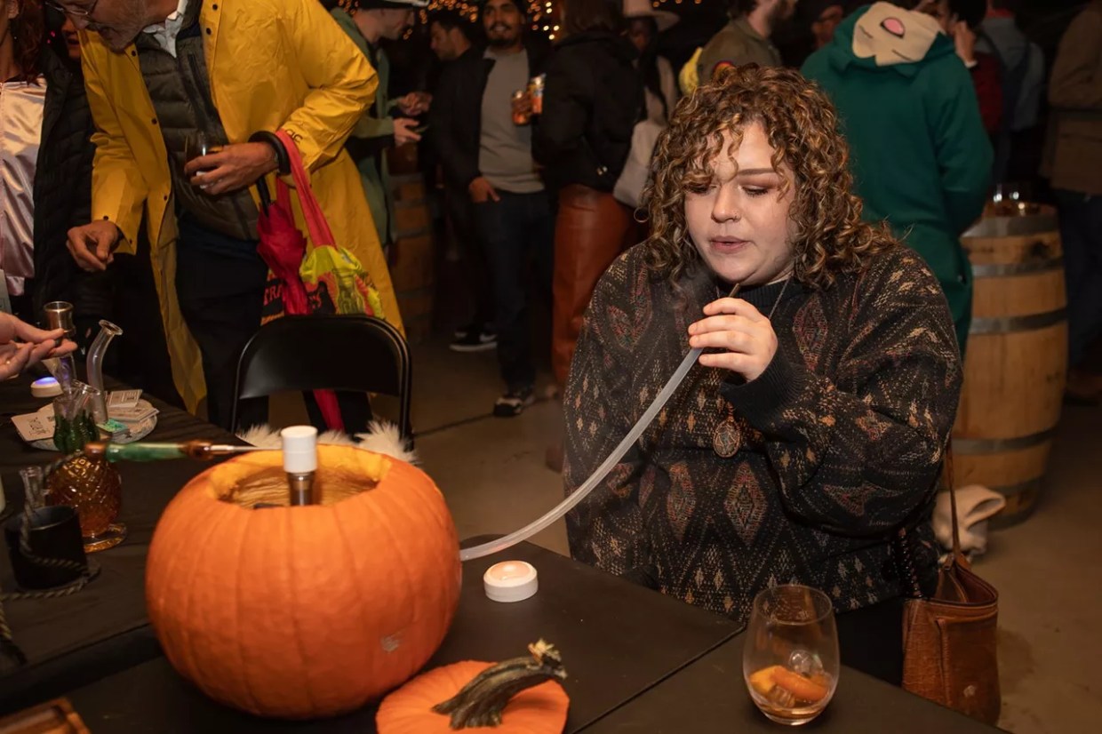 Woman smokes weed out of pumpkin hookah at halloween party
