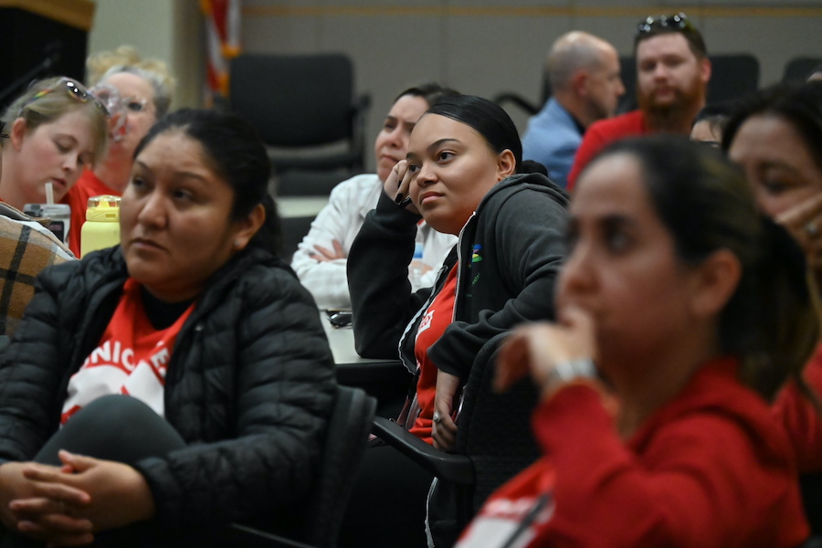 crowd of school workers listens to board meeting