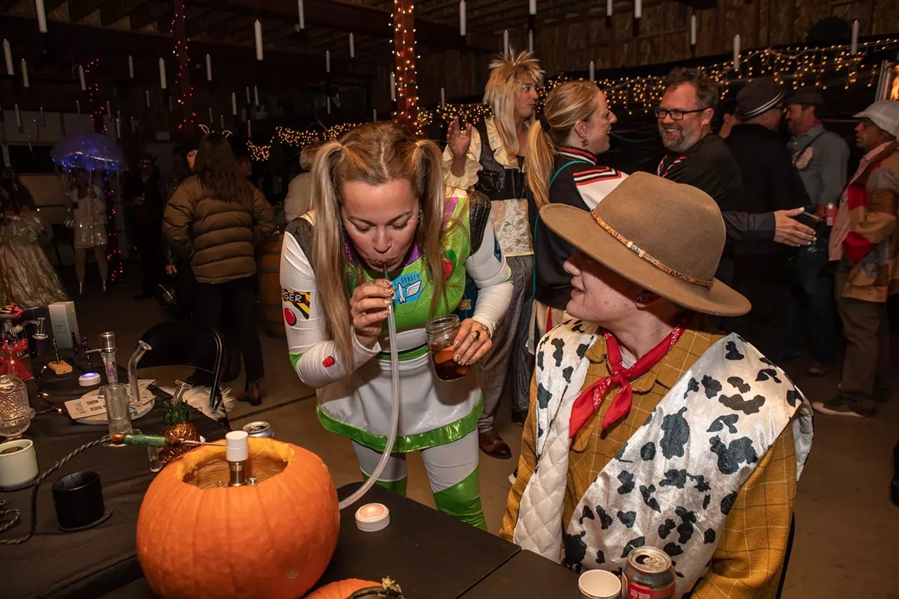 women dressed as buzz light-year and Woody smoke pumpkin hookah at Halloween party
