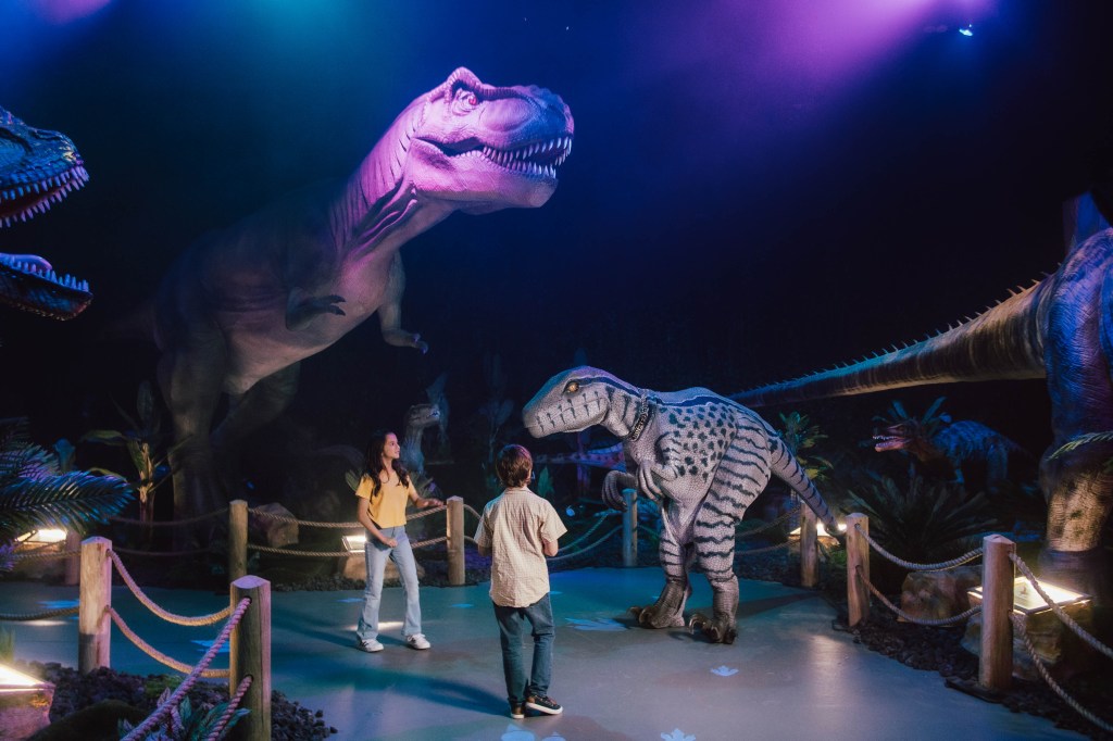 Children crowd around dinosaur animatronics.