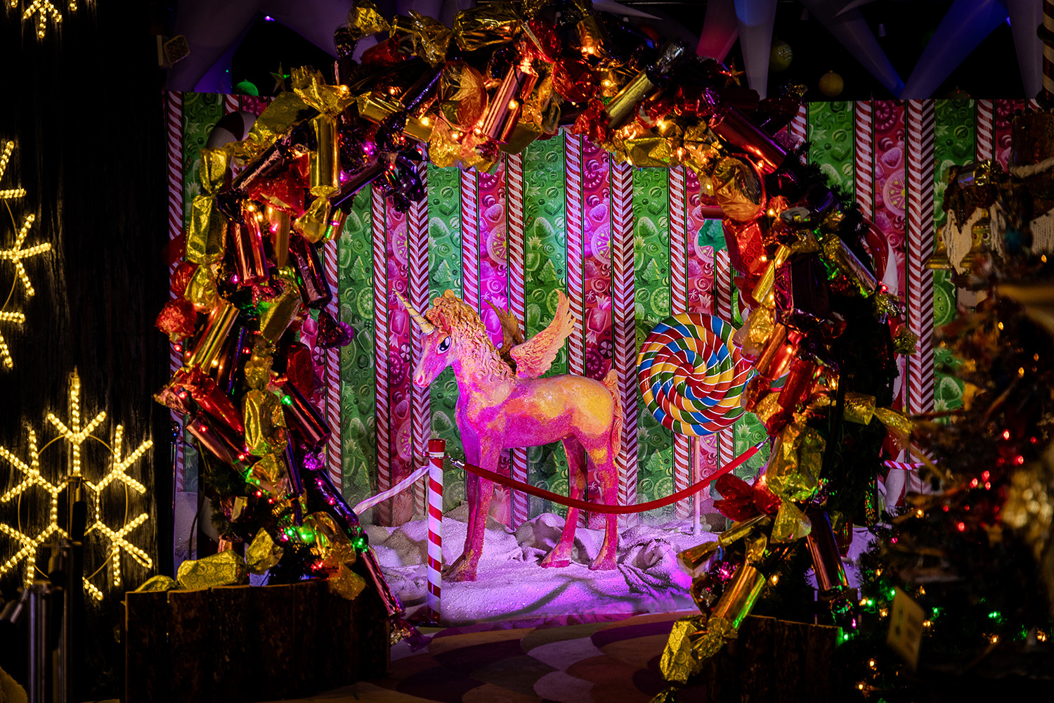 A pink unicorn is surrounded by Christmas decor.