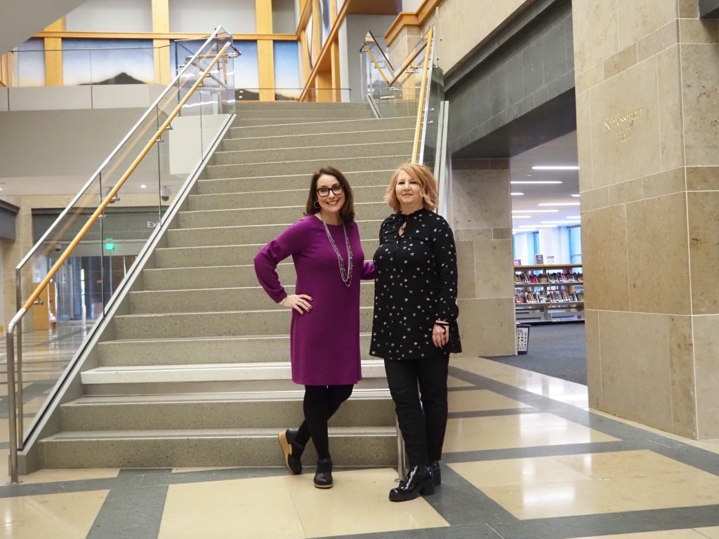 a portrait of two women standing by a staircase
