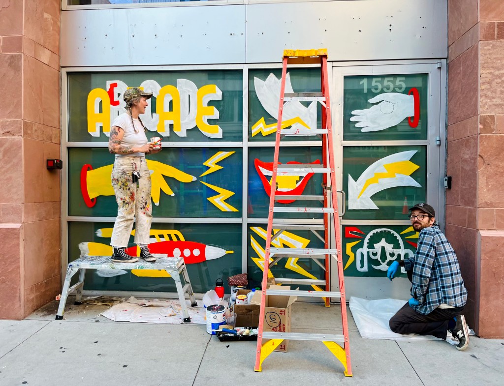 Storefront windows painted with images of hands, lightning, and a rocket ship.