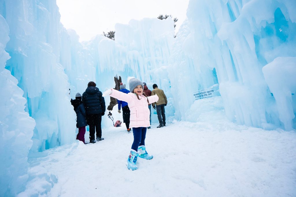 A young girl backdropped by tall walls made from icicles