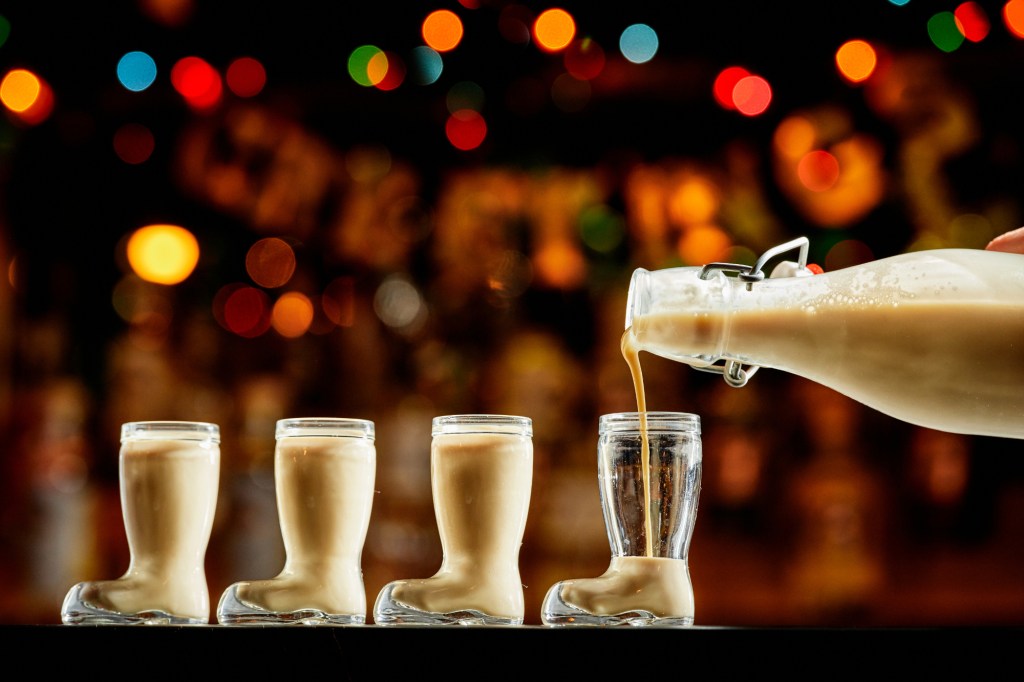 eggnog being poured into boot-shaped glasses