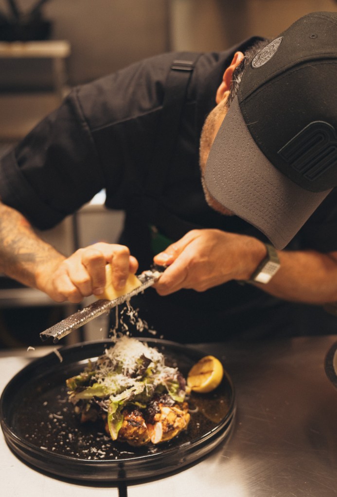 chef grating ingredient onto a dish