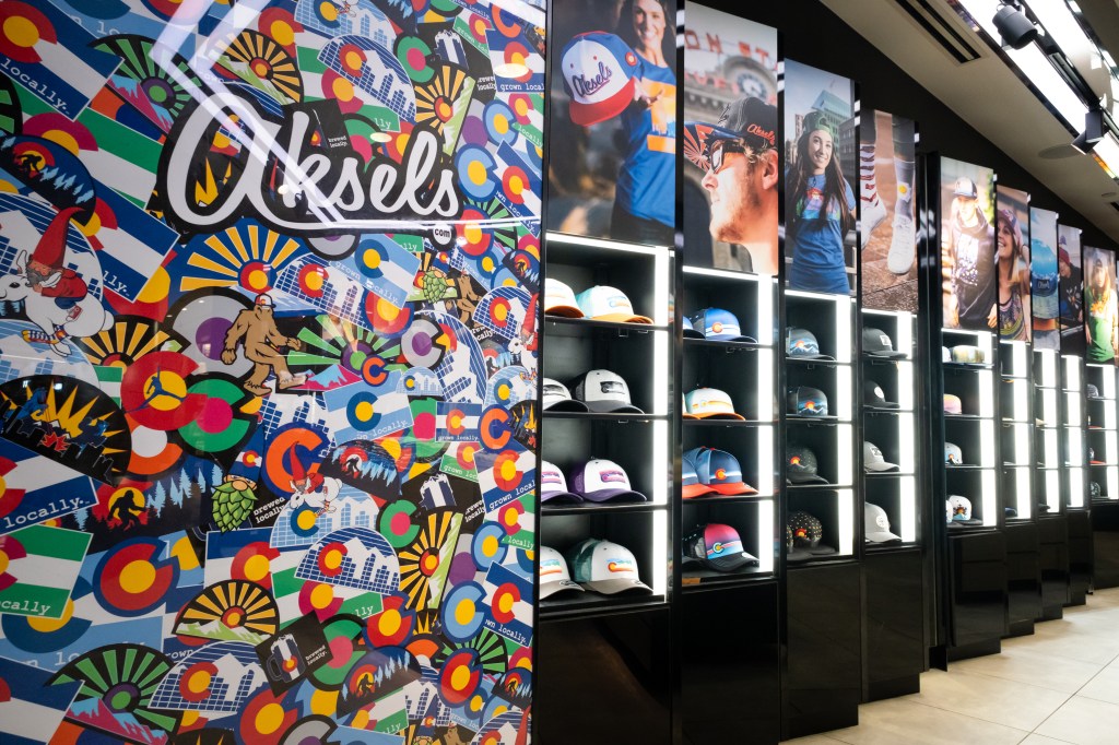 Display of Boston-themed hats and caps next to a colorful, artistic wall with the word "Boston" and various vibrant designs.