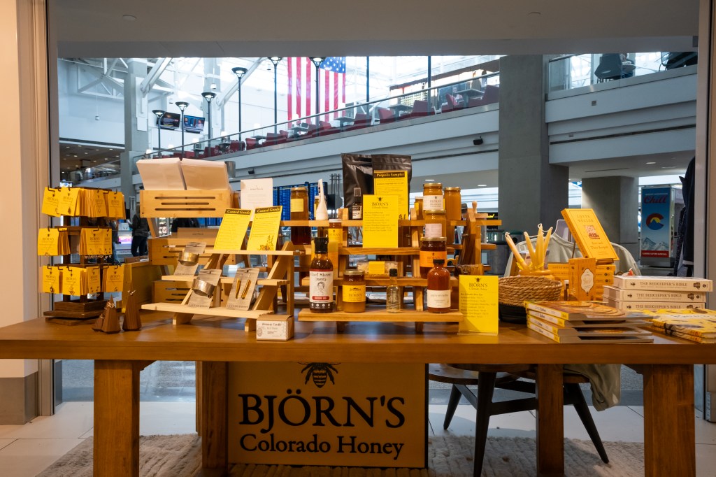 Display table with various jars of honey, pamphlets, and products at Bjorn's Colorado Honey booth in a mall.