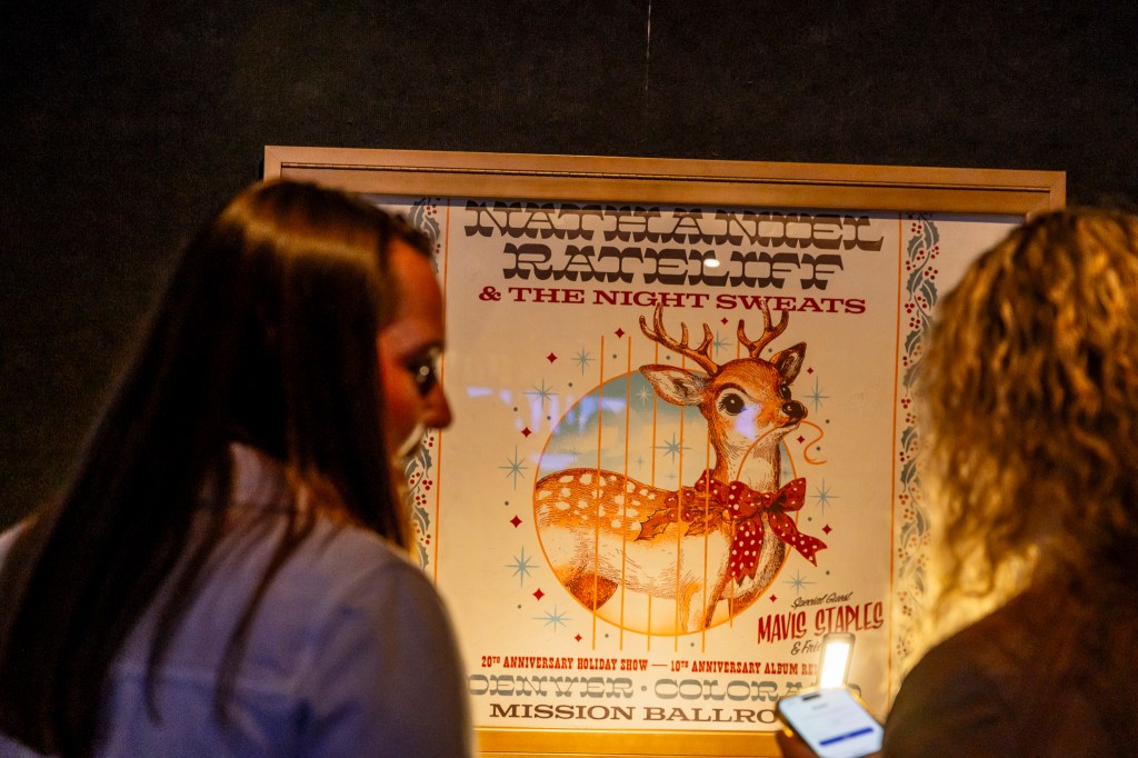 Concertgoers chat near a show poster at Mission Ballroom.