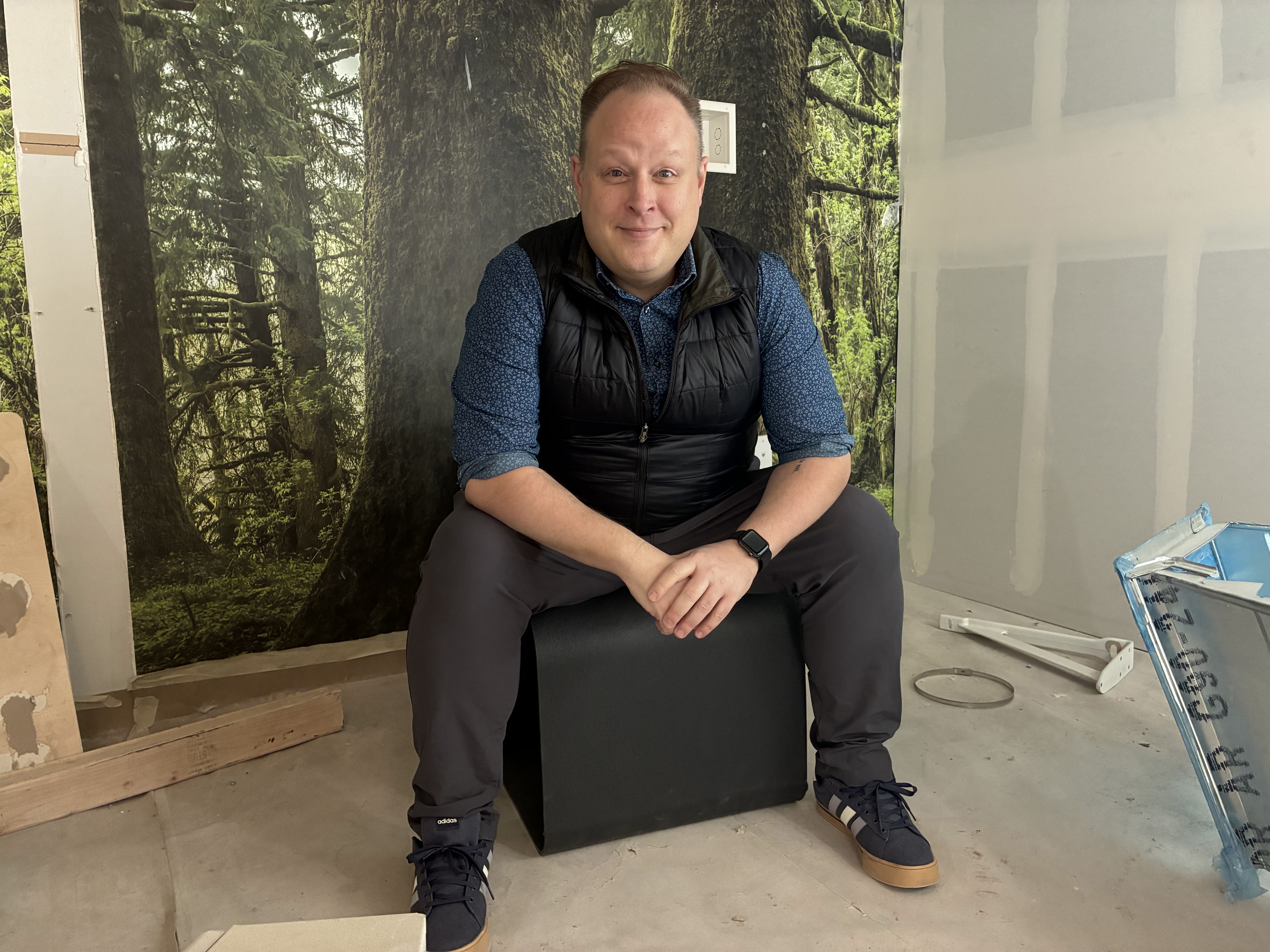 A man sits on a block inside a room under construction