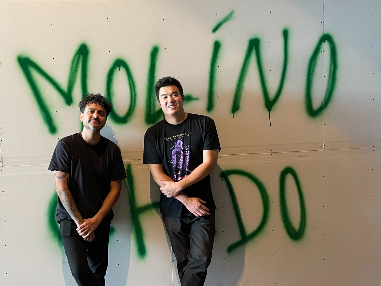 two men posing in front of graffiti