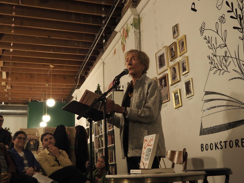 A woman reads poetry at a microphone