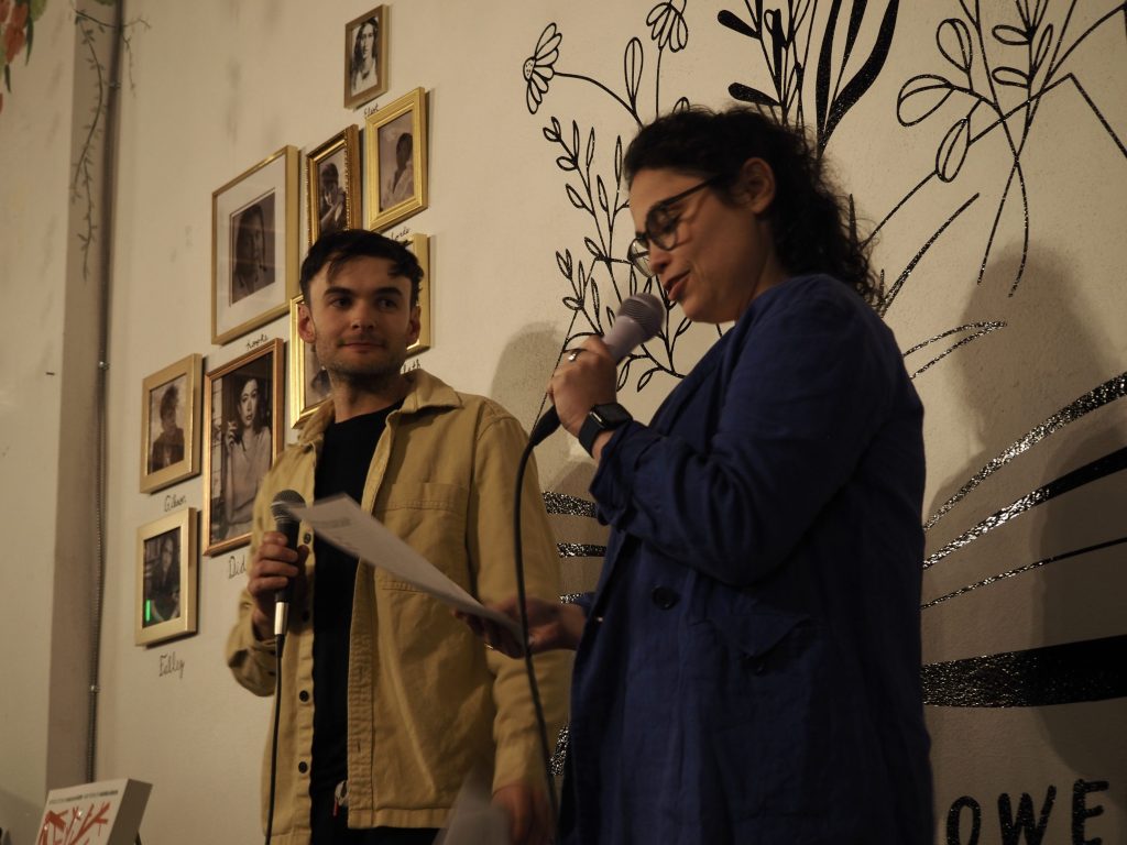 Two people stand at a microphone