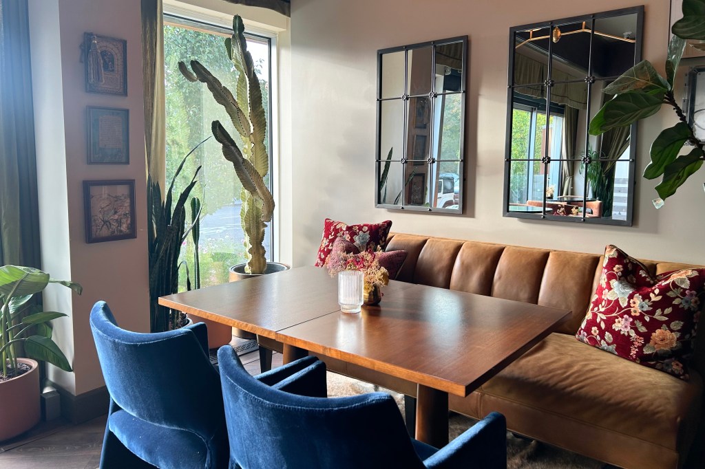 The interior of Wildflower featuring blue velvet seating, embroidered pillows and live plants