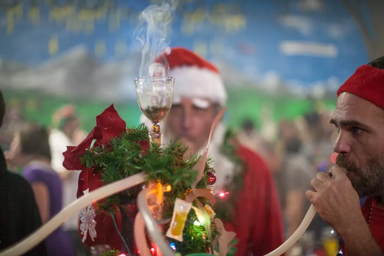 People smoke weed out of a hookah at a Christmas party.