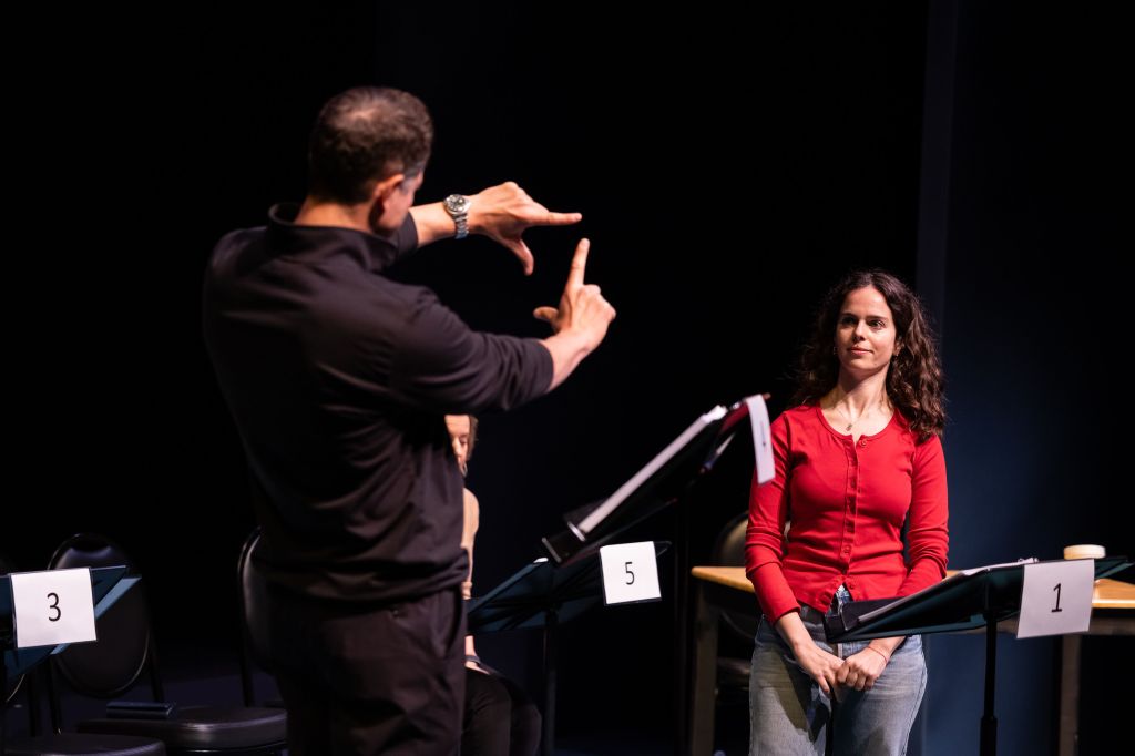Two actor perform behind rehearsal stands