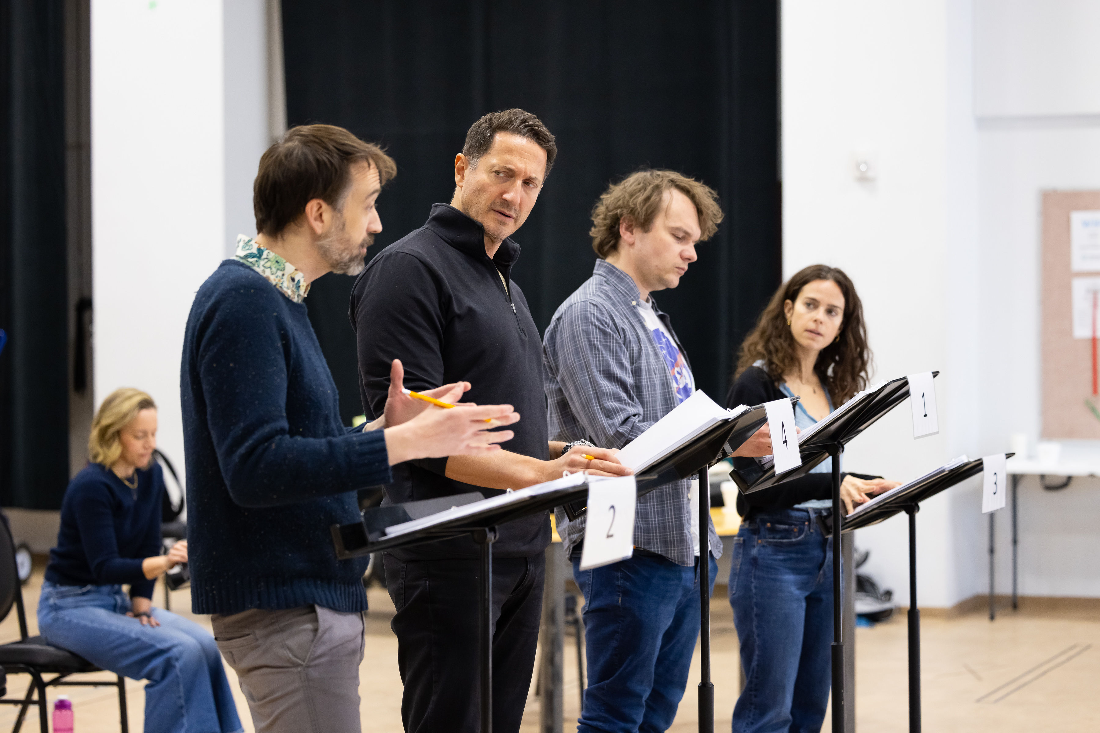 Actors stand at rehearsal stands