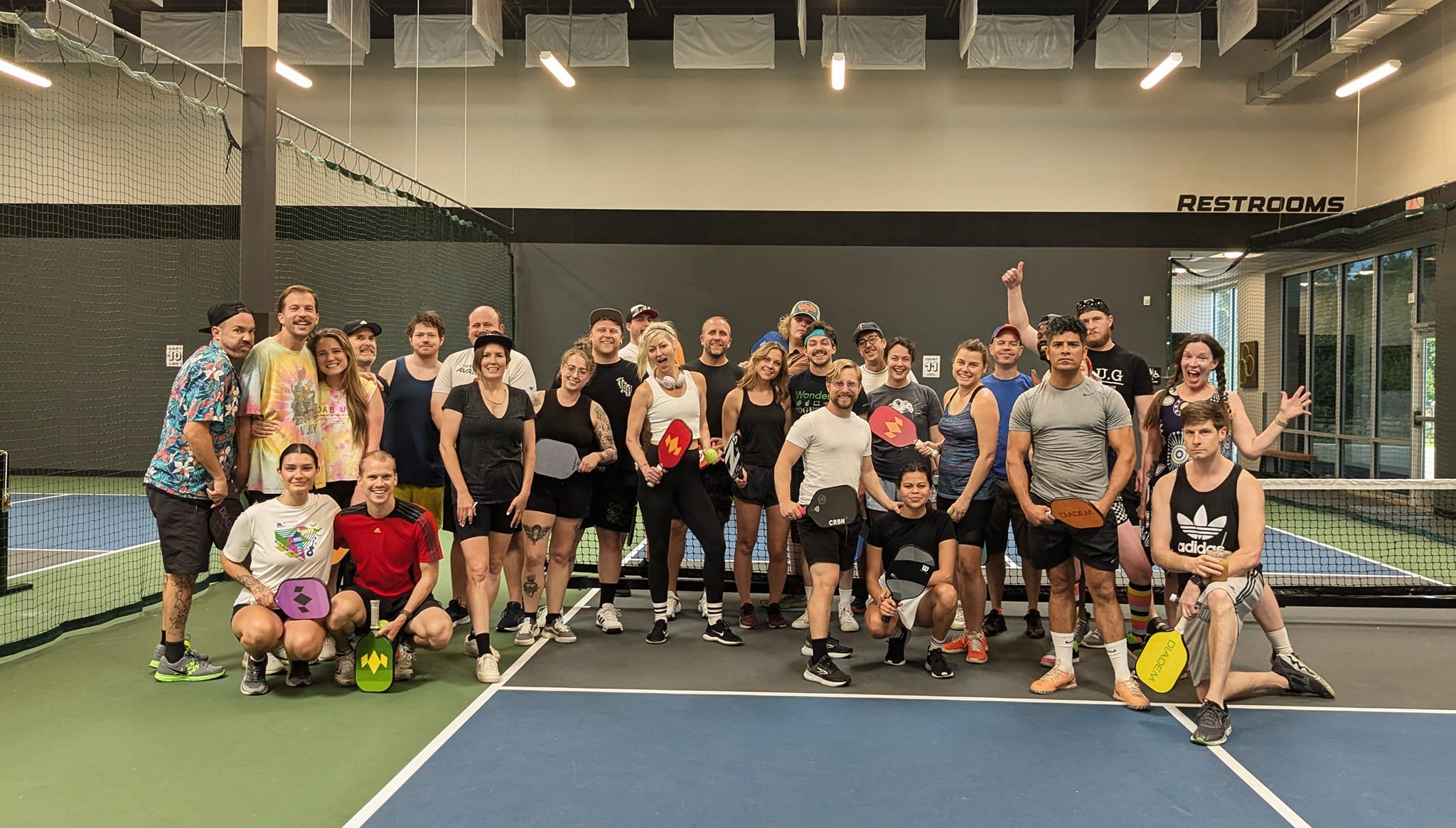 Comedian pose together on a pickleball court