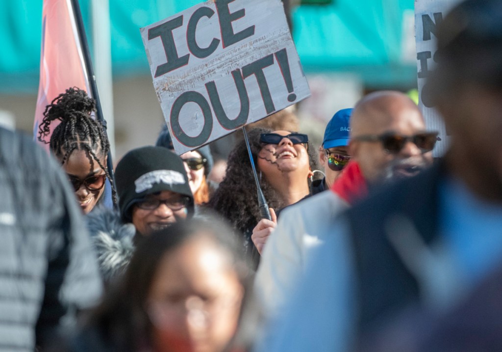 anti-ice protester holds sign