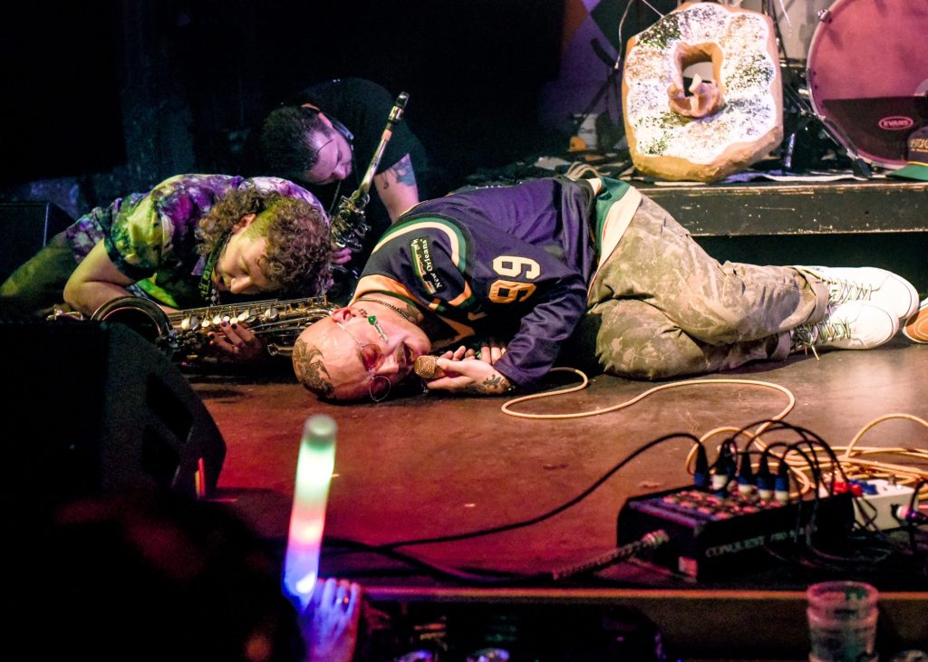 bandmates lying down on stage with their instruments while performing