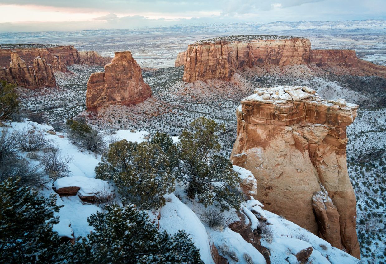 Large red rock formations and pinyon pines dusted with snow at Colorado National Monument