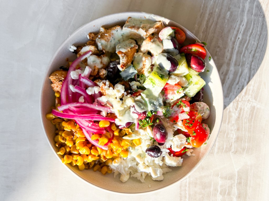 Grilled chicken, cherry tomatoes, olives and other ingredients in a Cava-inspired grain bowl