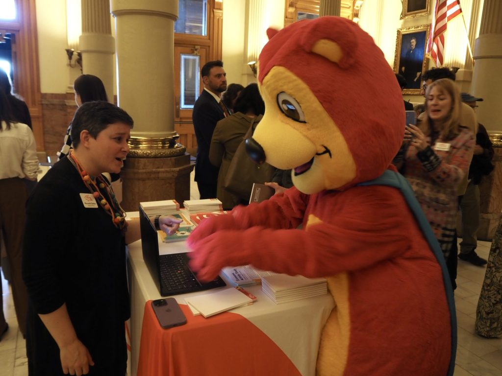 A pink bear types on a computer