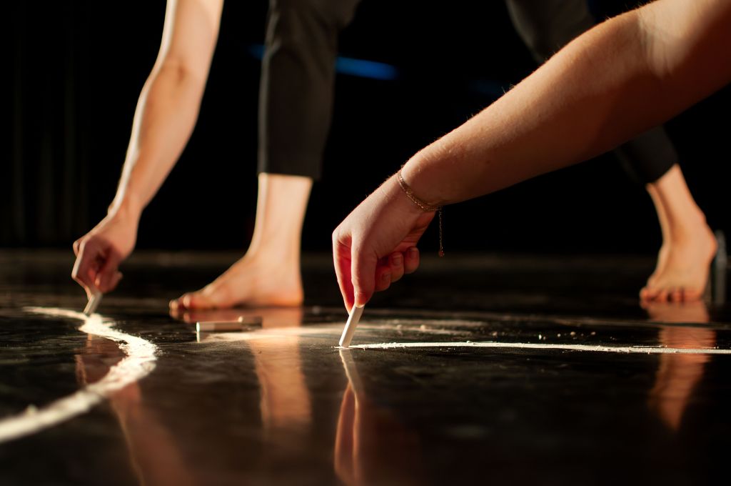 Dancers draw with chalk.