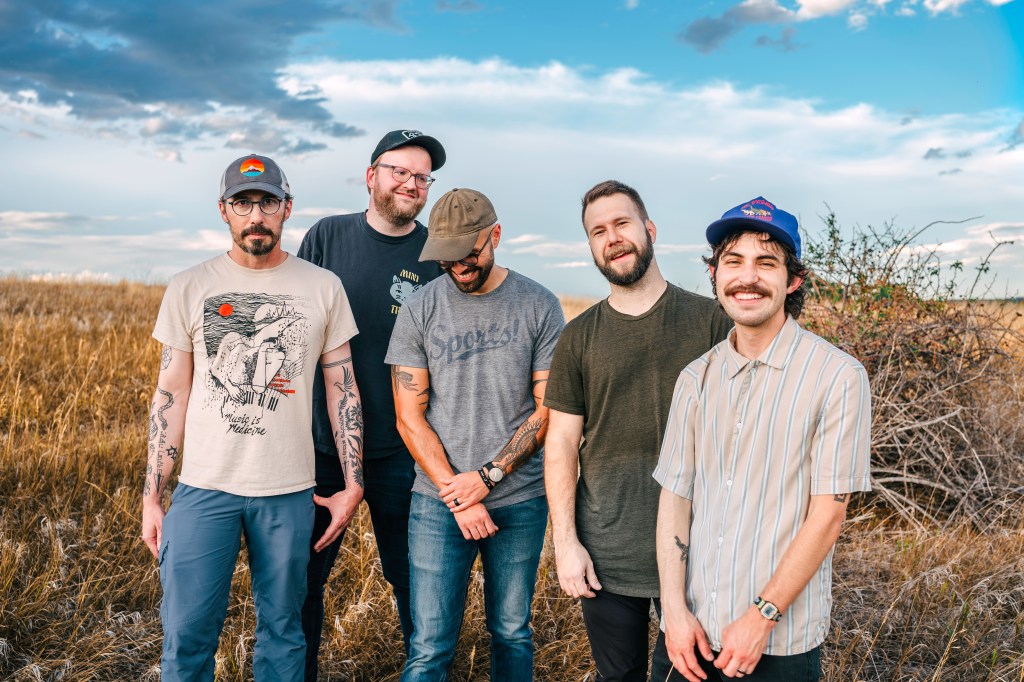 Five bandmembers standing in a field