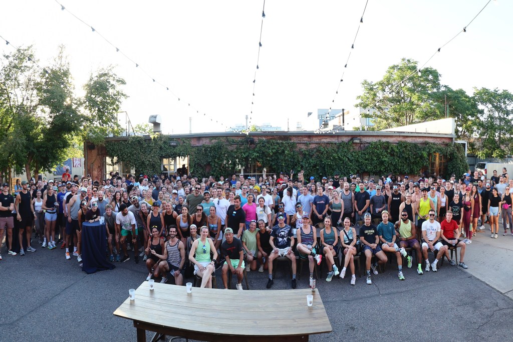 Dozens of people posed outdoors for a group photo during a Cooldown run club event in Denver