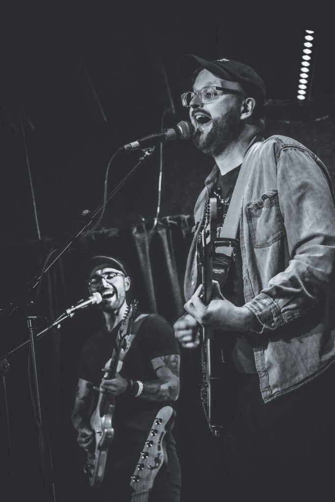 two people with guitars singing into microphones on stage