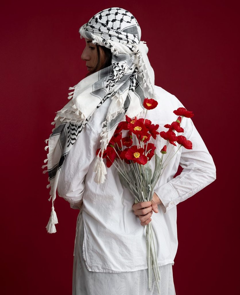 A woman in white holds red flowers behind her back
