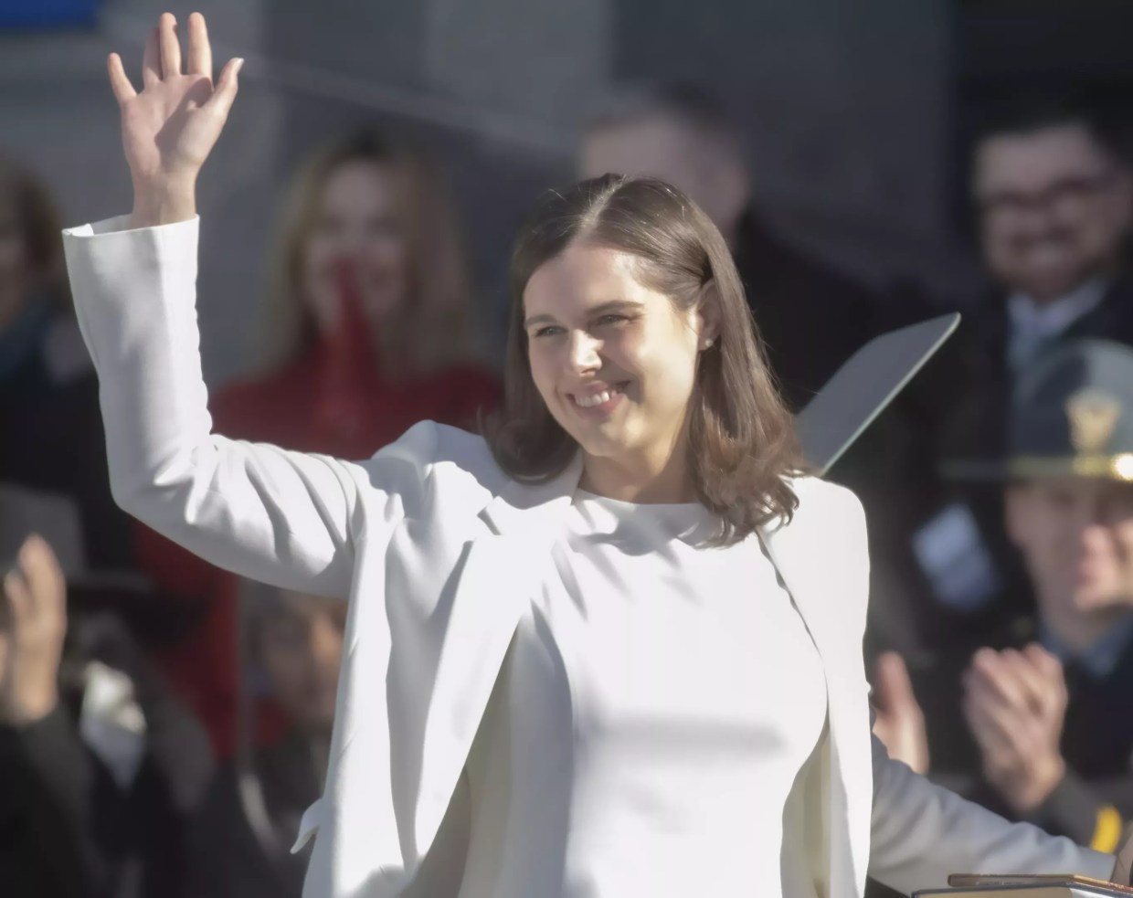 woman in white suit waving