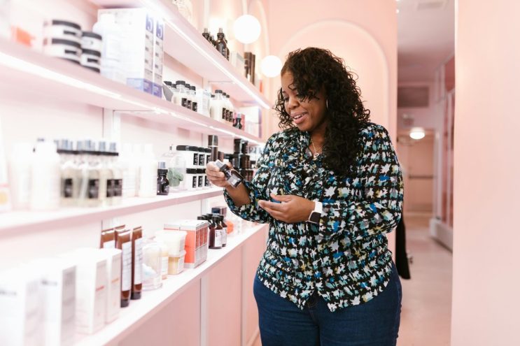 A woman inspects a hair-styling product as she shops.
