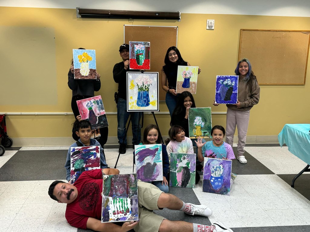 An artist poses with young artists and their work
