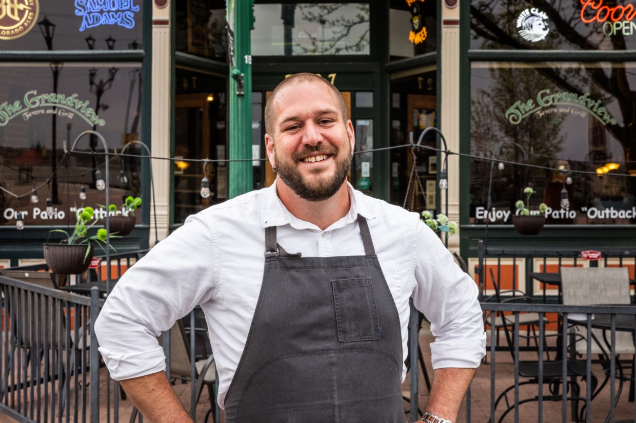 man in apron in front of a restaurant