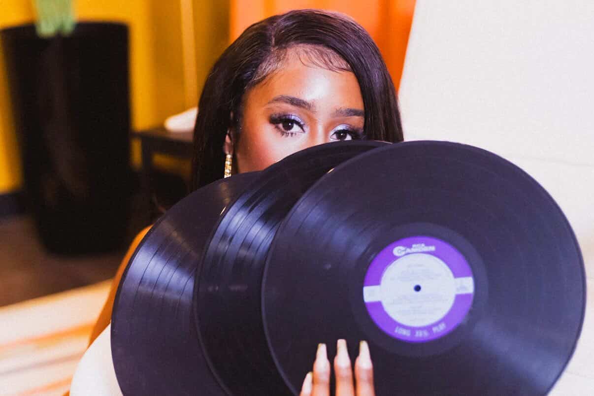 woman holding vinyl records in front of face