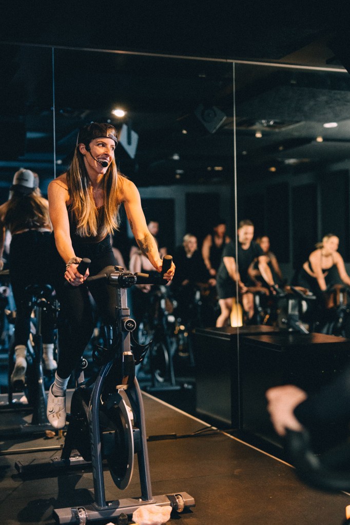 Brien on a stationary bike, leading a class at Ritual