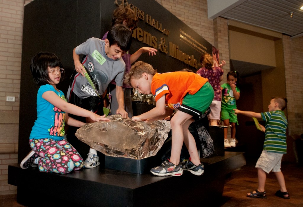 Kids play on specimens entrance to Coors Mineral Hall at DMNS.
