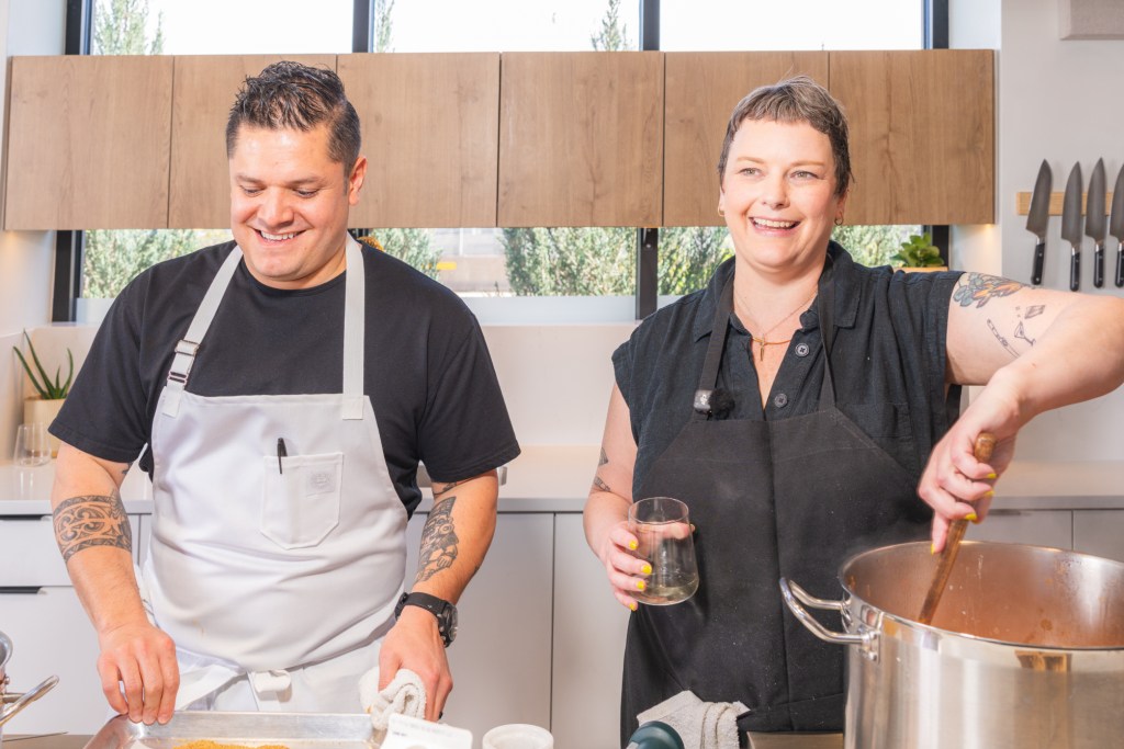 two people in aprons standing in a kitchen