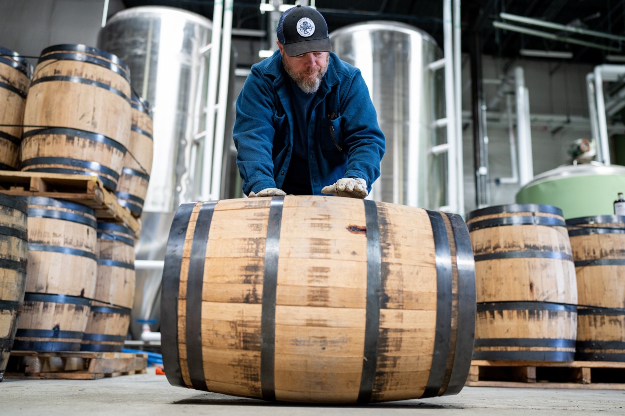 man pushing a barrel of whiskey
