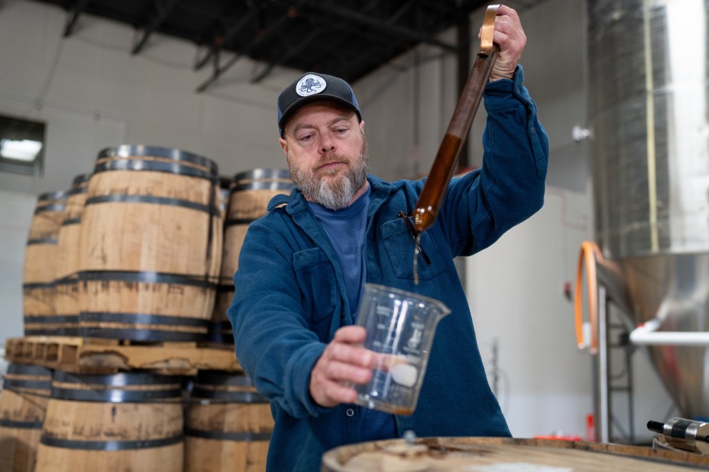 man pulling whiskey from a barrel