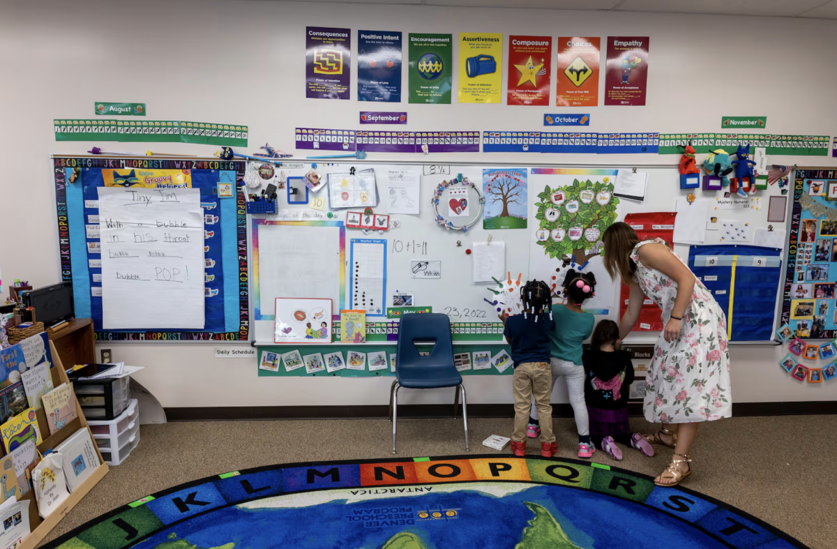 A school teacher helps young students at the white board