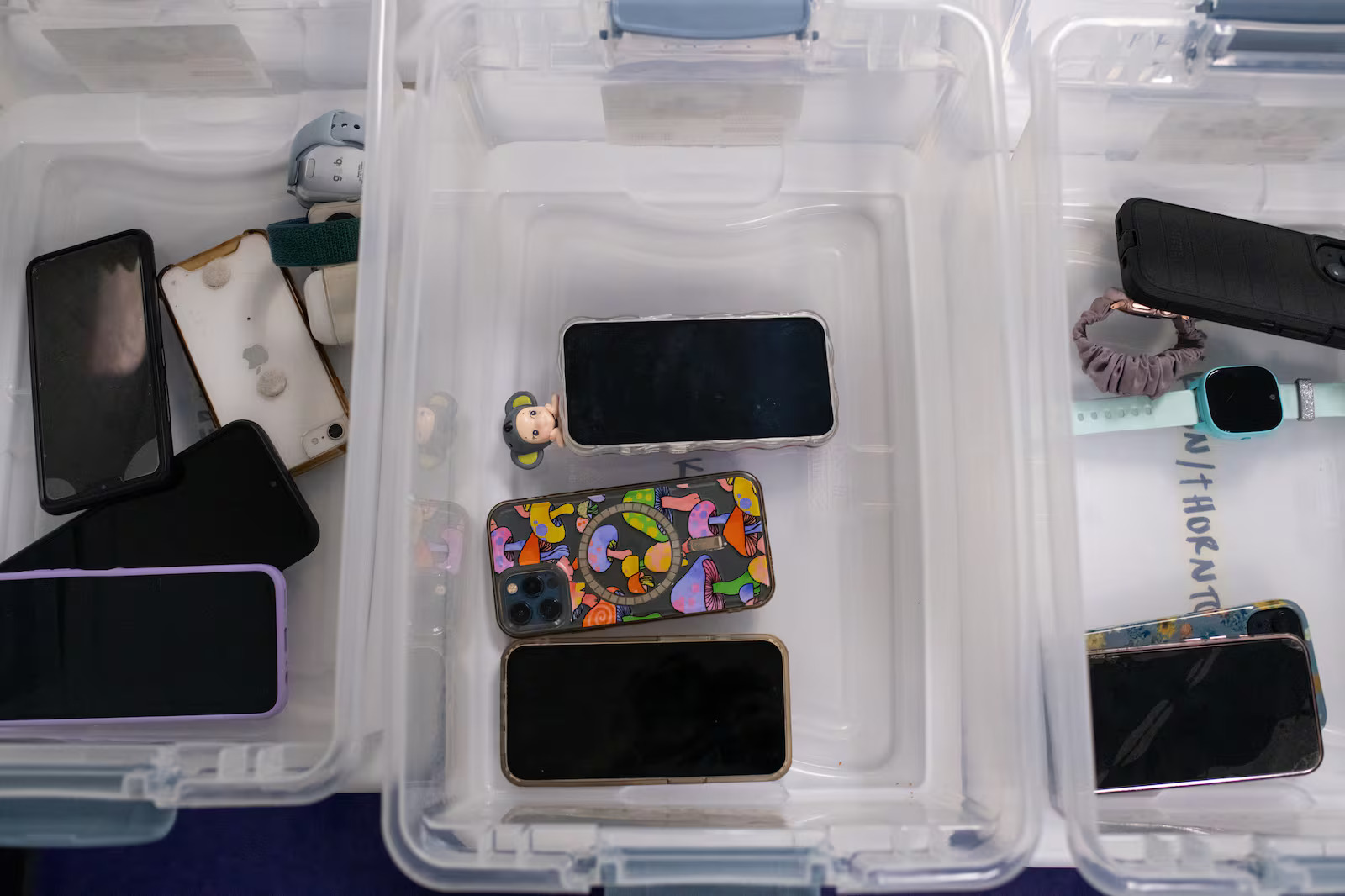 Students' cellphones sit in bins on a table