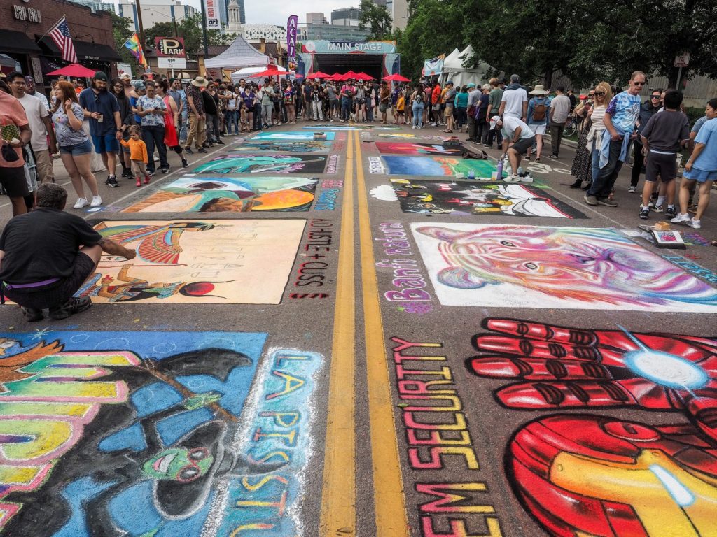 Artists working with chalk while a crowd watches