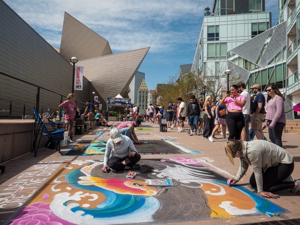 Artists working with chalk while a crowd watches