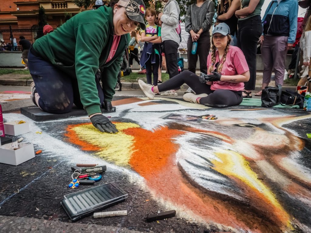 Artist working with chalk while a crowd watches